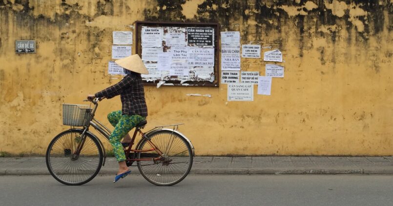 Vietnamita con gorro paseando en bicicleta