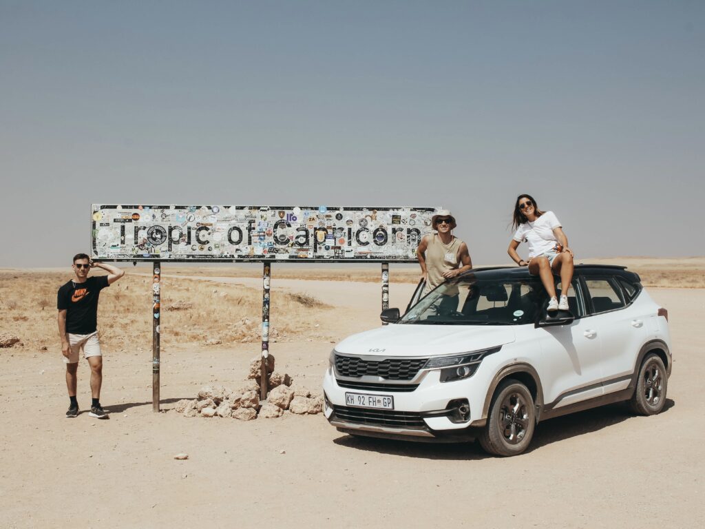Foto con el coche de alquiler en el cartel del trópico de Capricornio