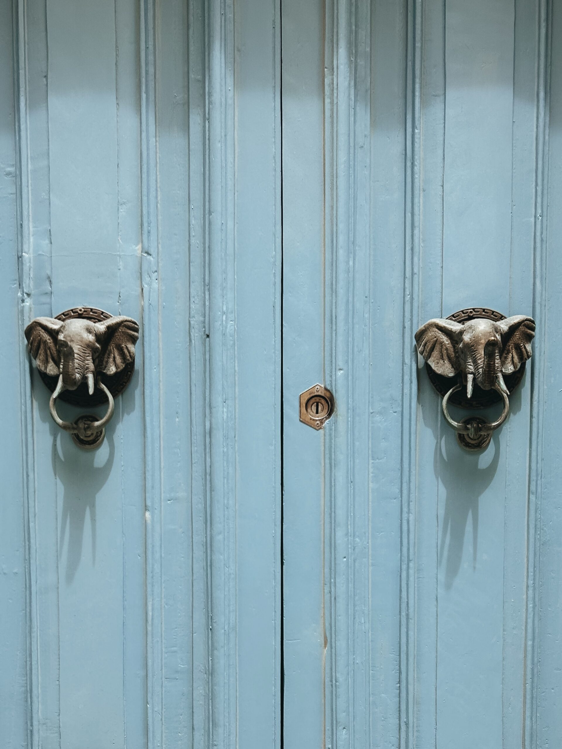 puerta de color azul con llamadores de elefante