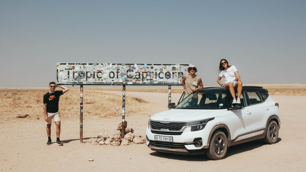Foto con el coche de alquiler en el cartel del trópico de Capricornio