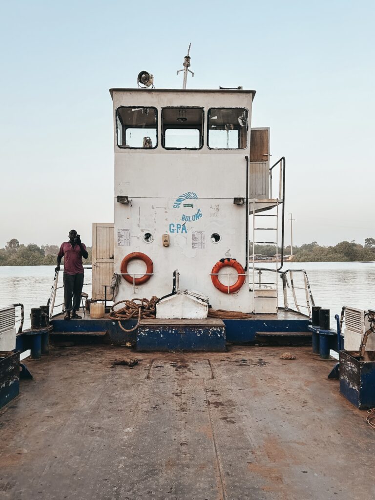 Tras 15 min de conducción llegamos a la zona donde tenemos que subir la furgoneta a un ferry para transportarlo hasta la isla de Jangjabureh, la distancia es corta de apenas 20-30 metros lo separan, pero no hay puente y tenemos que desplazarnos de esta manera.
