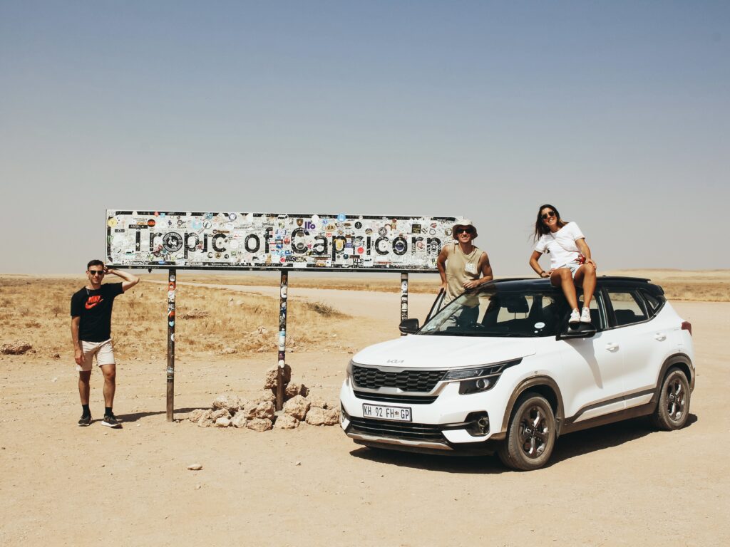 Foto con el coche de alquiler en el cartel del trópico de Capricornio