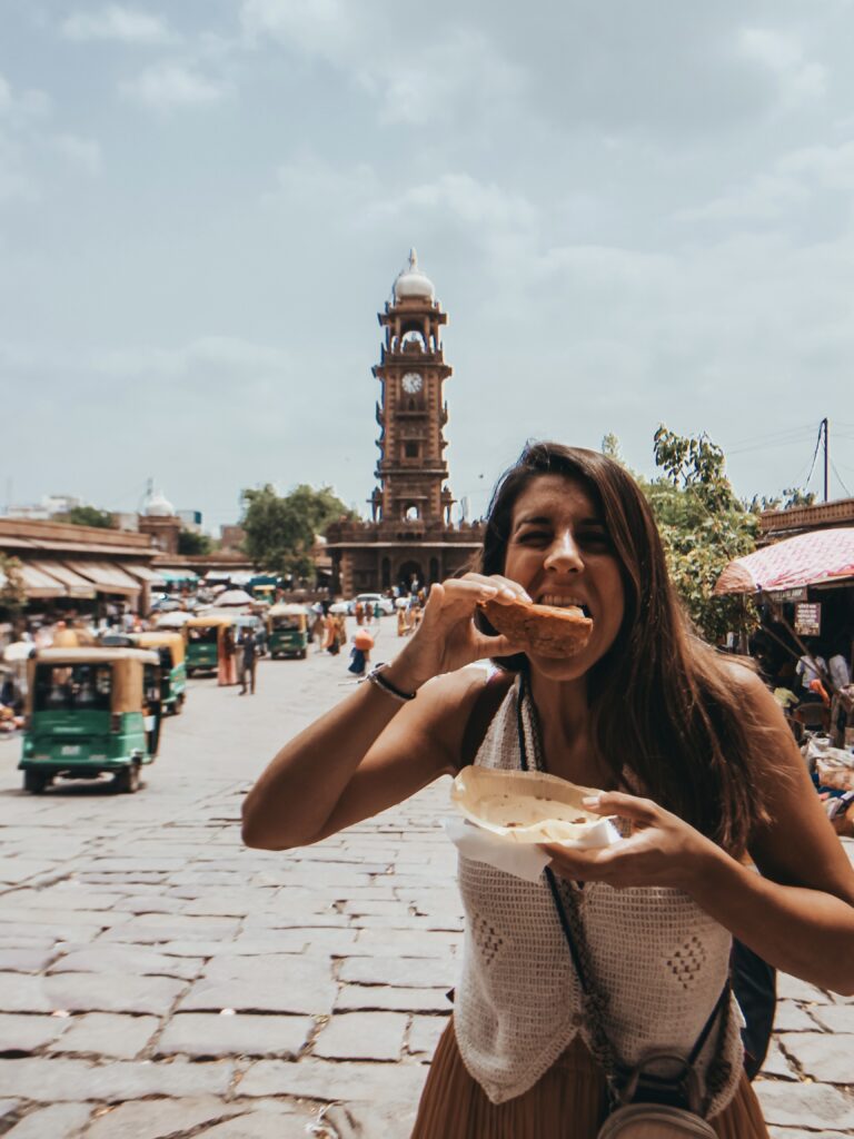 Noelia comiendo una samosa en el Sardar Market con la Torre del Reloj de fondo