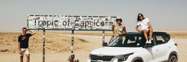 Foto con el coche de alquiler en el cartel del trópico de Capricornio